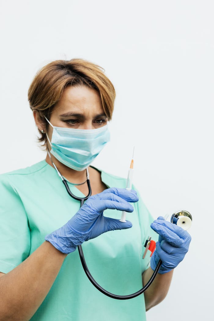 Nurse preparing a syringe for vaccination, wearing a face mask and gloves.